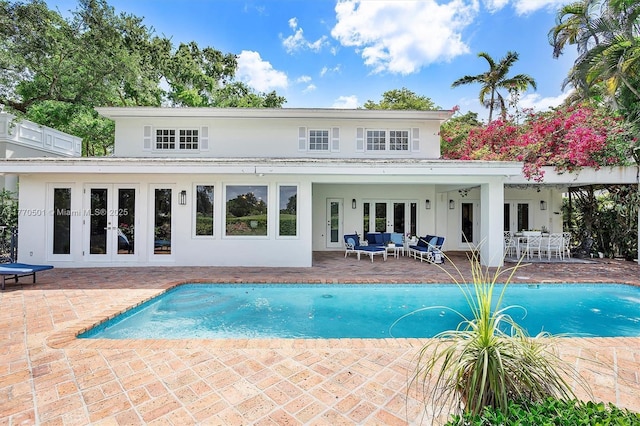 back of house with french doors, a patio, stucco siding, and an outdoor pool