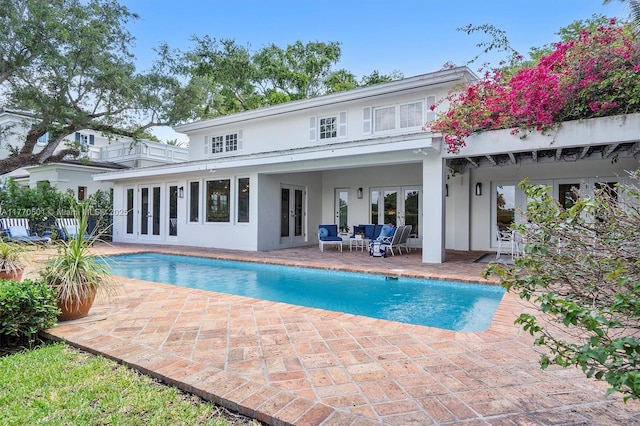 back of house featuring a patio, an outdoor pool, stucco siding, and french doors