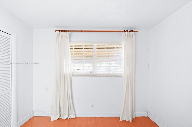 unfurnished room with baseboards and wood finished floors