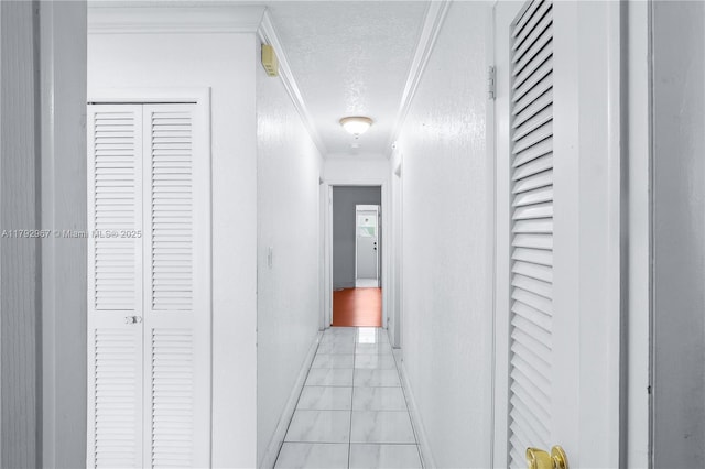hall with baseboards, ornamental molding, marble finish floor, and a textured ceiling