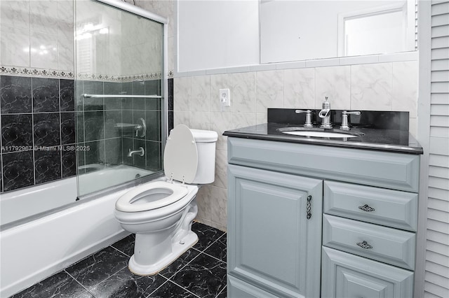 full bathroom featuring toilet, tile walls, shower / bath combination with glass door, and vanity