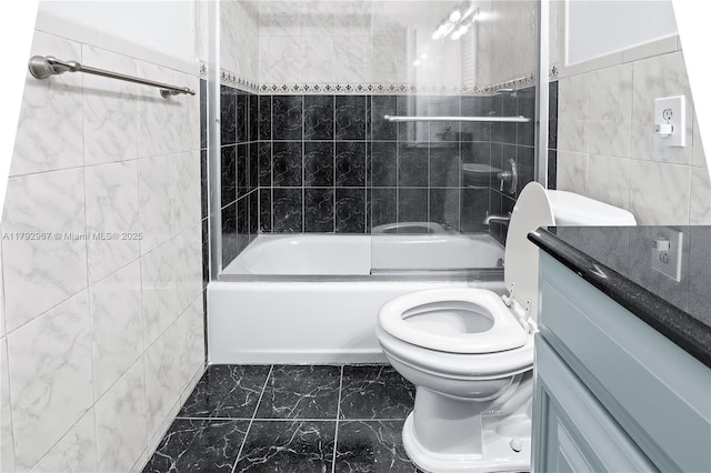 bathroom with vanity, marble finish floor, toilet, tile walls, and shower / bathing tub combination