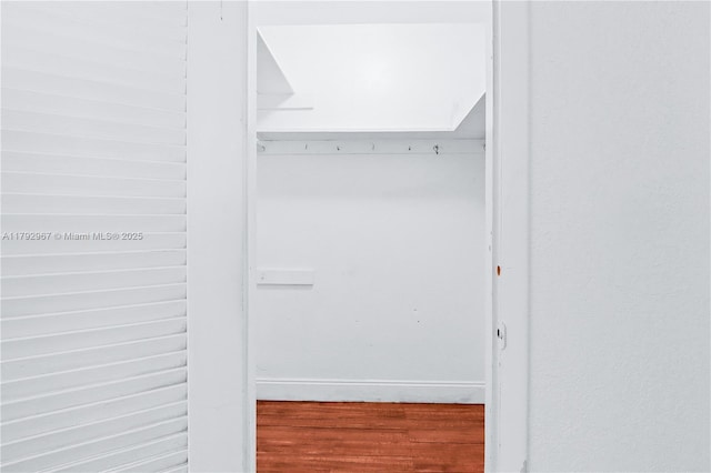 walk in closet with wood finished floors