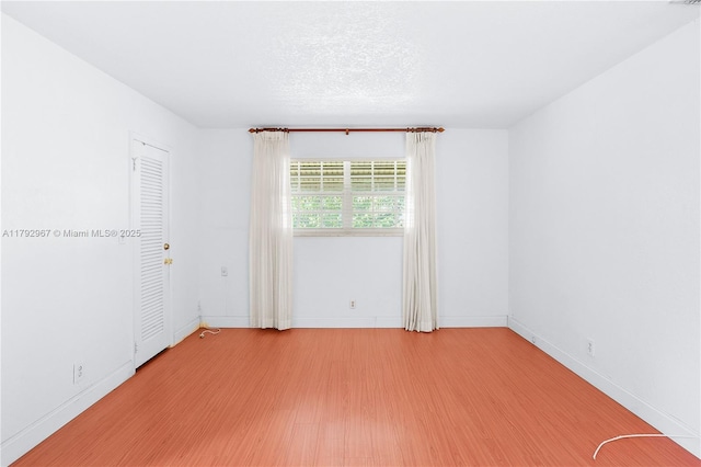 unfurnished room with baseboards and light wood-type flooring