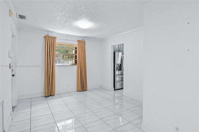spare room with crown molding, a textured ceiling, visible vents, and baseboards