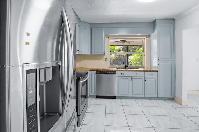 kitchen featuring light tile patterned flooring, appliances with stainless steel finishes, a sink, gray cabinets, and tasteful backsplash