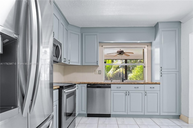 kitchen featuring decorative backsplash, dark countertops, a ceiling fan, light tile patterned floors, and stainless steel appliances