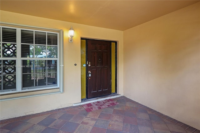 view of exterior entry featuring covered porch and stucco siding