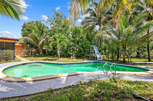 outdoor pool featuring a patio area, a water slide, and fence