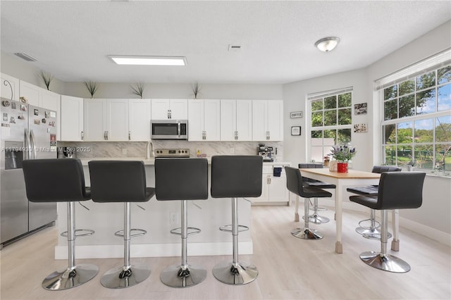 kitchen with white cabinets, stainless steel appliances, and light wood-type flooring