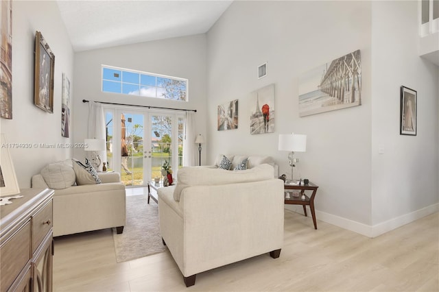 living area with french doors, visible vents, high vaulted ceiling, baseboards, and light wood-style floors