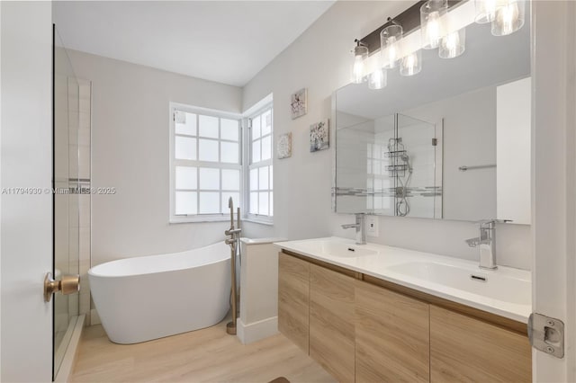full bath featuring a sink, a freestanding tub, double vanity, and wood finished floors