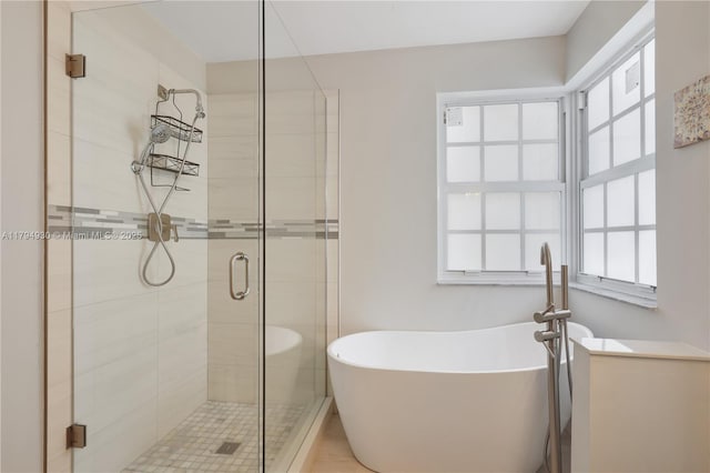 bathroom featuring a freestanding bath, plenty of natural light, and a shower stall
