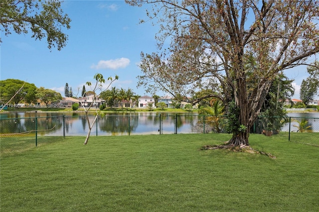 exterior space with a lawn, a water view, and fence