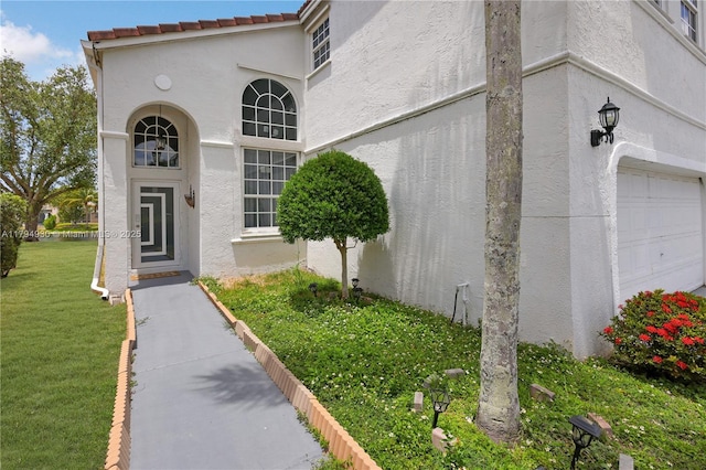 doorway to property with a yard and stucco siding