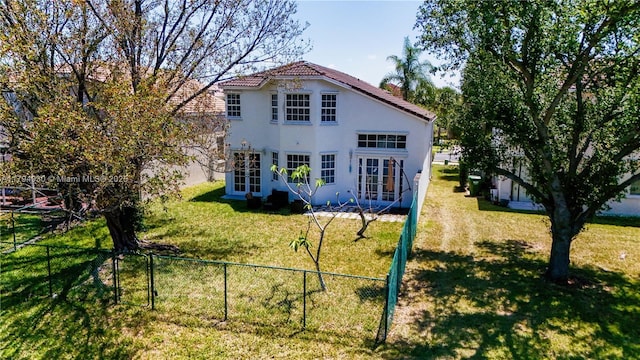 view of front of property with fence, stucco siding, a front yard, french doors, and a tiled roof