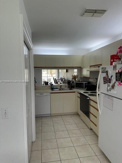 575 Augusta Blvd Unit 8, Naples, FL 34113 - kitchen featuring visible vents, a sink, light tile patterned floors, under cabinet range hood, and white appliances