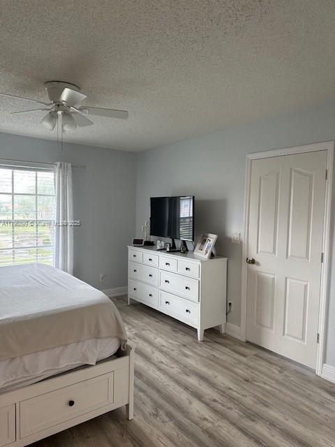 575 Augusta Blvd Unit 8, Naples, FL 34113 - bedroom with a textured ceiling, ceiling fan, baseboards, and light wood finished floors