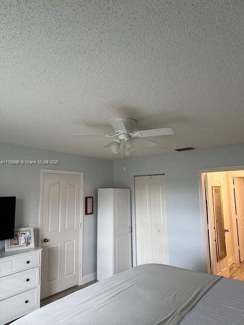 575 Augusta Blvd Unit 8, Naples, FL 34113 - bedroom with a ceiling fan, a textured ceiling, visible vents, and a closet