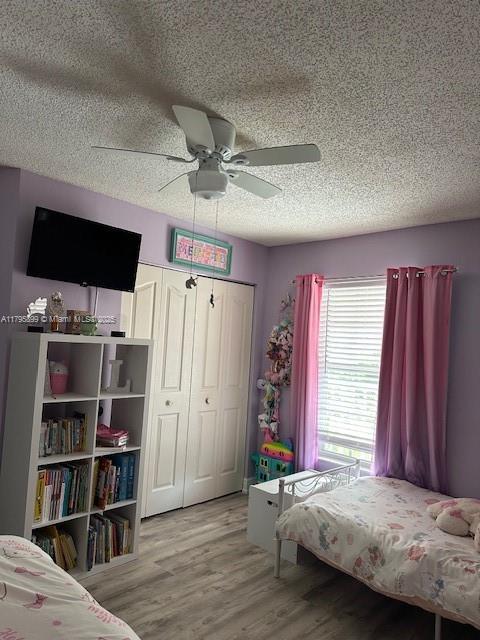 575 Augusta Blvd Unit 8, Naples, FL 34113 - bedroom with a closet, a ceiling fan, a textured ceiling, and wood finished floors