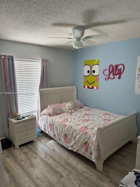 575 Augusta Blvd Unit 8, Naples, FL 34113 - bedroom featuring a ceiling fan, a textured ceiling, and wood finished floors