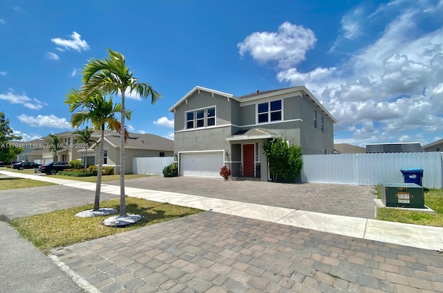 traditional-style house featuring a residential view, a garage, decorative driveway, fence, and stucco siding