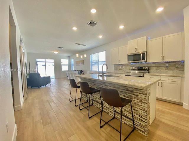 kitchen featuring visible vents, decorative backsplash, light wood-type flooring, a sink, and appliances with stainless steel finishes