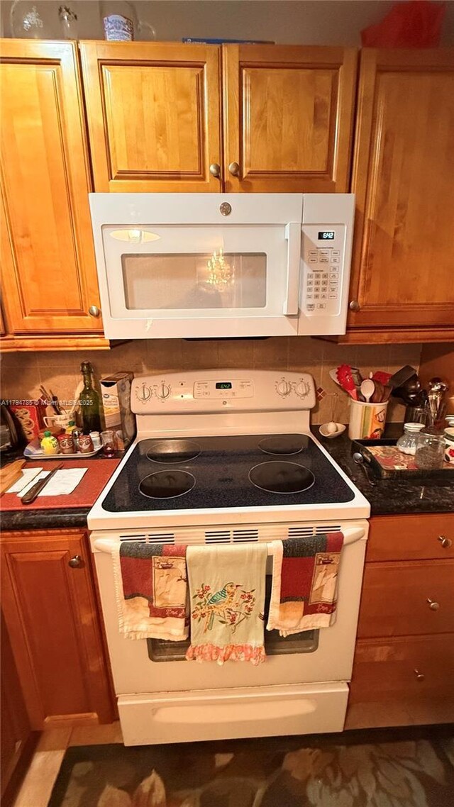 4330 Hillcrest Dr Unit 214, Hollywood, FL 33021 - kitchen with white appliances, brown cabinets, backsplash, and dark countertops