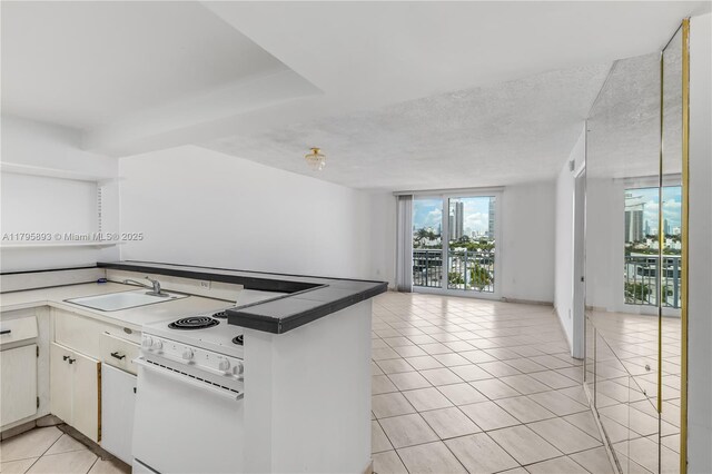 345 Ocean Dr Unit 904, Miami Beach, FL 33139 - kitchen featuring white electric range oven, light tile patterned floors, open floor plan, a wall of windows, and a peninsula