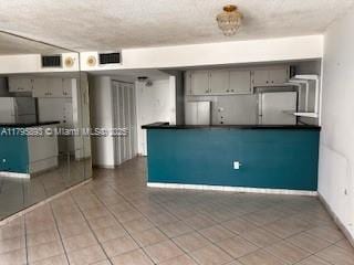 345 Ocean Dr Unit 904, Miami Beach, FL 33139 - kitchen with dark countertops, gray cabinets, tile patterned floors, and refrigerator