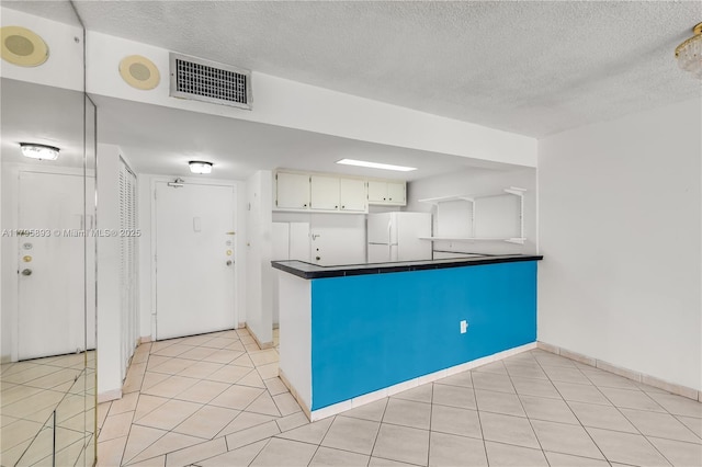 345 Ocean Dr Unit 904, Miami Beach, FL 33139 - kitchen featuring freestanding refrigerator, a textured ceiling, dark countertops, a peninsula, and light tile patterned flooring