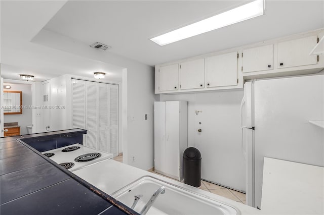 345 Ocean Dr Unit 904, Miami Beach, FL 33139 - kitchen featuring freestanding refrigerator, white cabinets, and light tile patterned floors