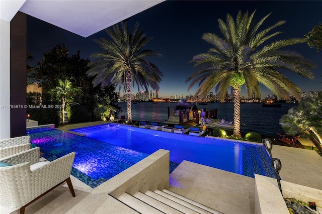 pool at twilight with a water view and an outdoor pool