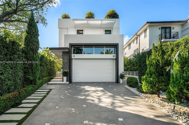 contemporary home featuring stairway, aphalt driveway, stucco siding, and a balcony