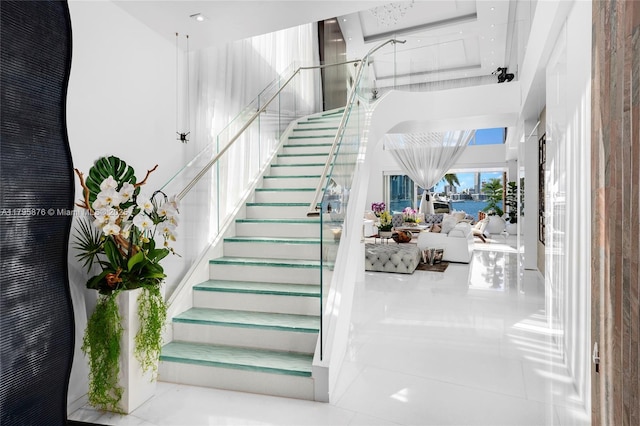 stairway featuring tile patterned flooring and a high ceiling