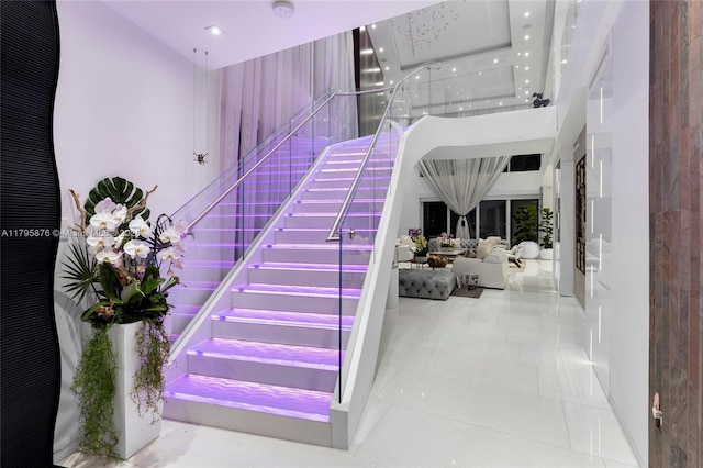 stairs with tile patterned flooring and a towering ceiling