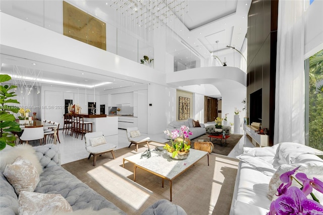 living area with a towering ceiling, arched walkways, and a healthy amount of sunlight