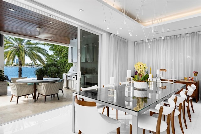dining area with a tray ceiling, a water view, and recessed lighting