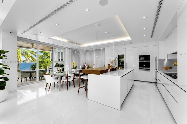 kitchen featuring white cabinetry, a raised ceiling, black microwave, and modern cabinets