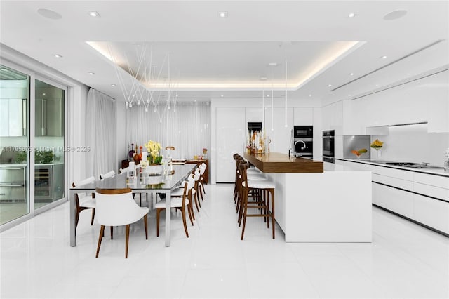 dining room featuring a tray ceiling and light tile patterned floors