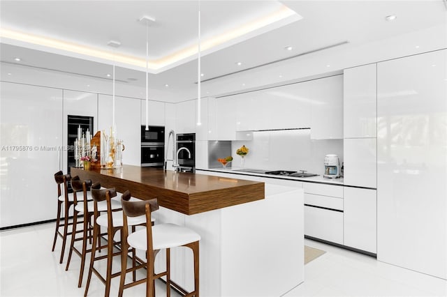 kitchen featuring a tray ceiling, black microwave, modern cabinets, and white cabinets