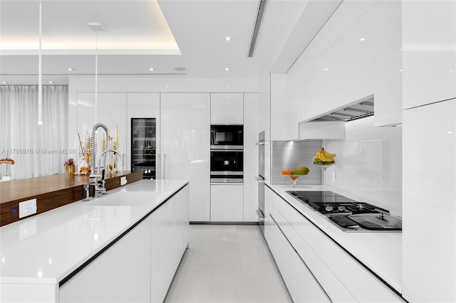 kitchen with light tile patterned floors, stovetop, white cabinetry, modern cabinets, and light countertops