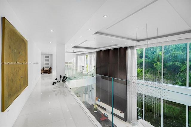 corridor featuring light tile patterned floors, a tray ceiling, and recessed lighting
