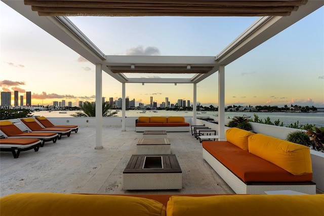 patio terrace at dusk with an outdoor hangout area, a water view, and a view of city