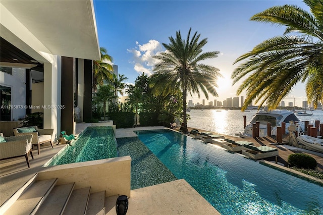 outdoor pool with a water view and a patio