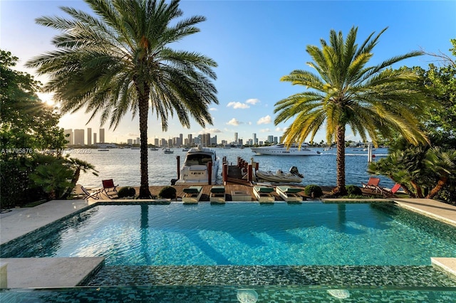 view of pool featuring a city view, a water view, an infinity pool, and a dock