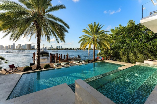 view of swimming pool featuring a pool with connected hot tub, a view of city, a dock, and a water view