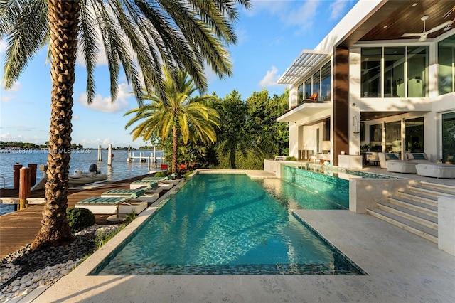 pool featuring a dock, a patio, a water view, and a ceiling fan