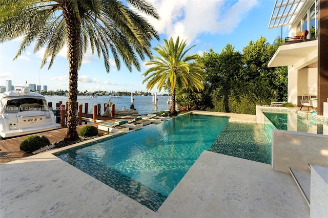 pool featuring a patio area, a water view, and a dock