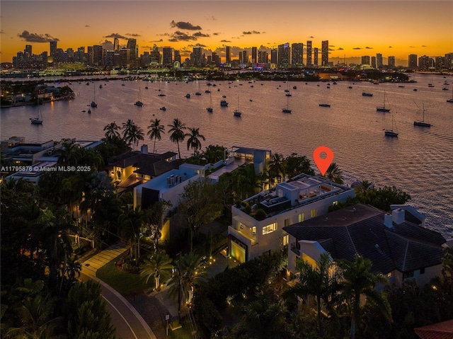 aerial view at dusk featuring a water view and a city view